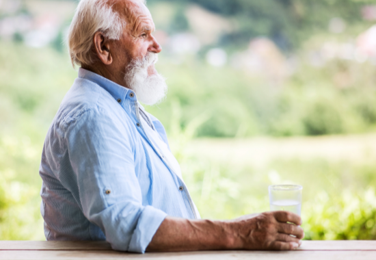 Hypothetical POMALYST® (pomalidomide) patient with relapsed/refractory multiple myeloma sitting outdoors holding onto a glass of water
